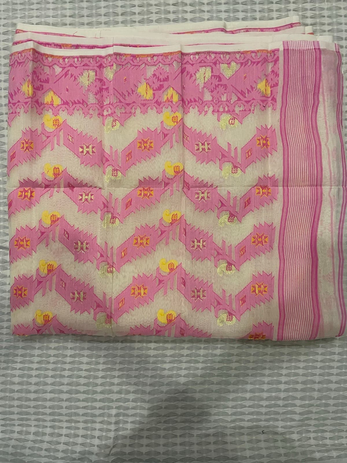 Jamdani saree collection on a bed